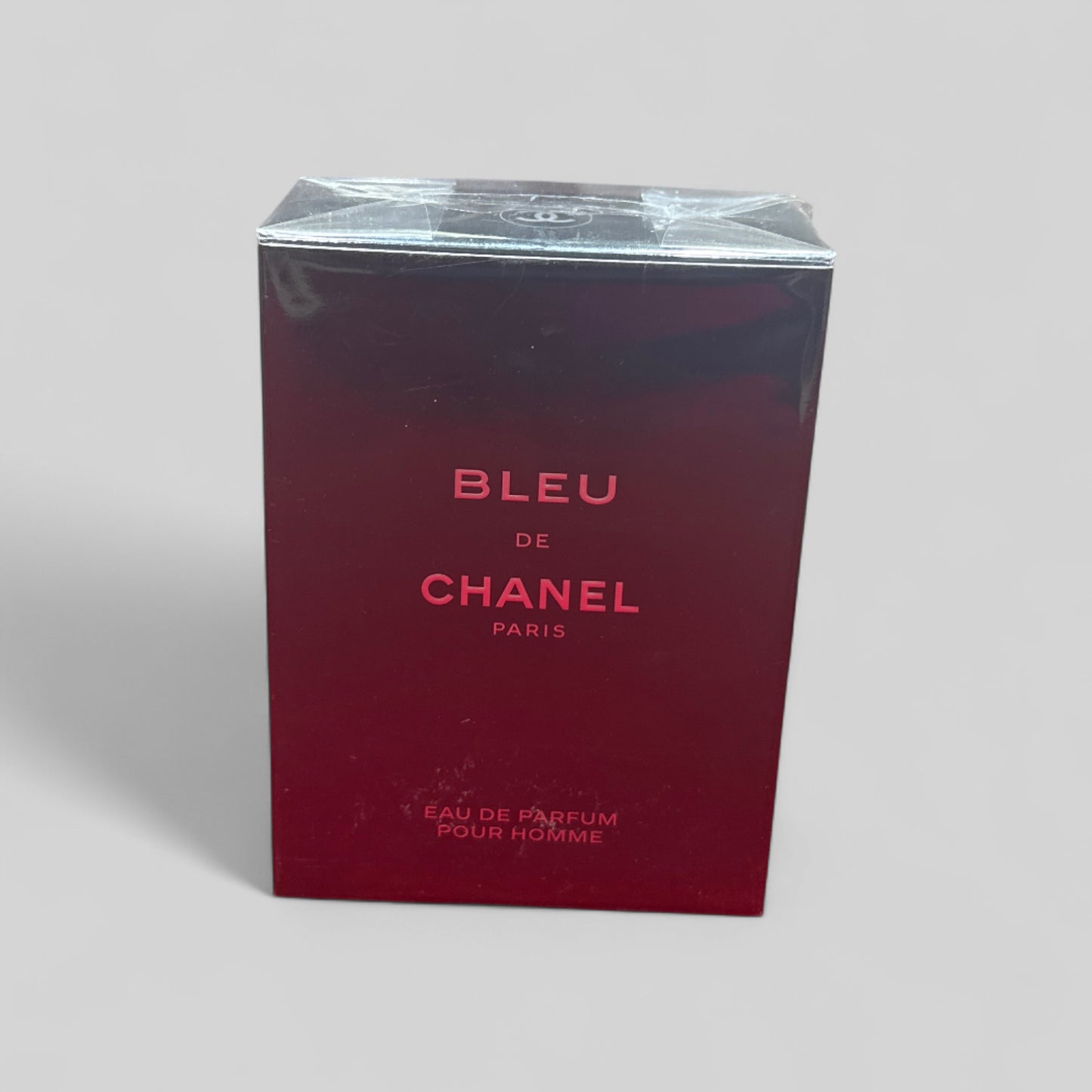 Red box of Bleu de Chanel perfume on a light gray background